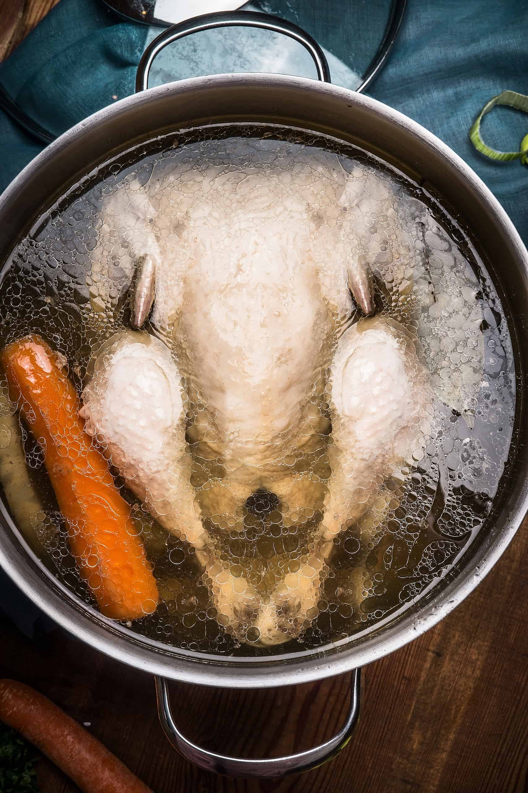 Whole chicken and carrot simmering in a stock pot, the slow-cooked chicken bone broth inside NutriFlex® Instant Chicken Bone Broth for dogs and cats
